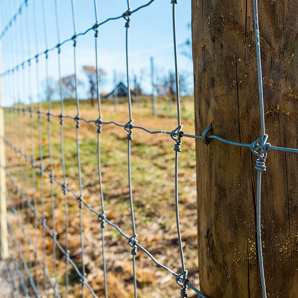 Galvanized woven farm fence attached to a wooden post for cattle, sheep and goat projects