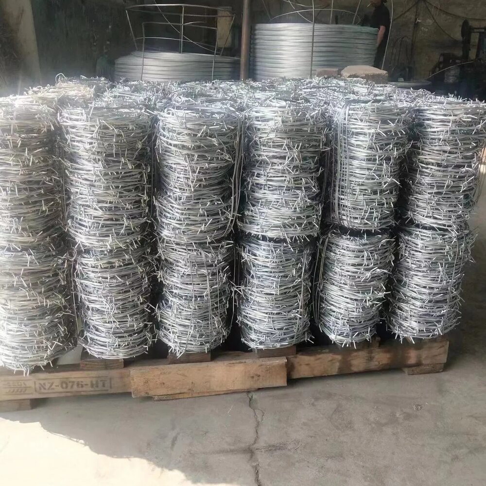 Factory stock of 14 gauge high tensile 4-point galvanized barbed wire coils on pallets