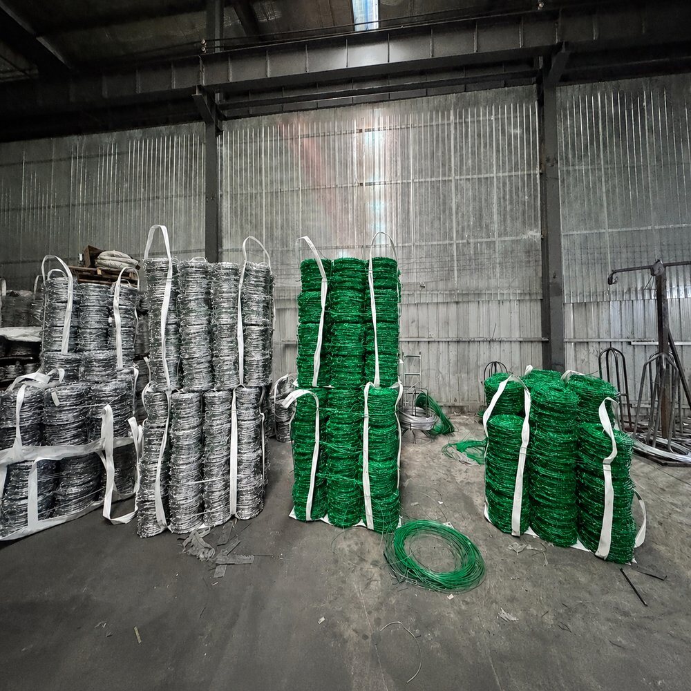 Galvanized and coated barbed wire coils bundled in factory warehouse stock
