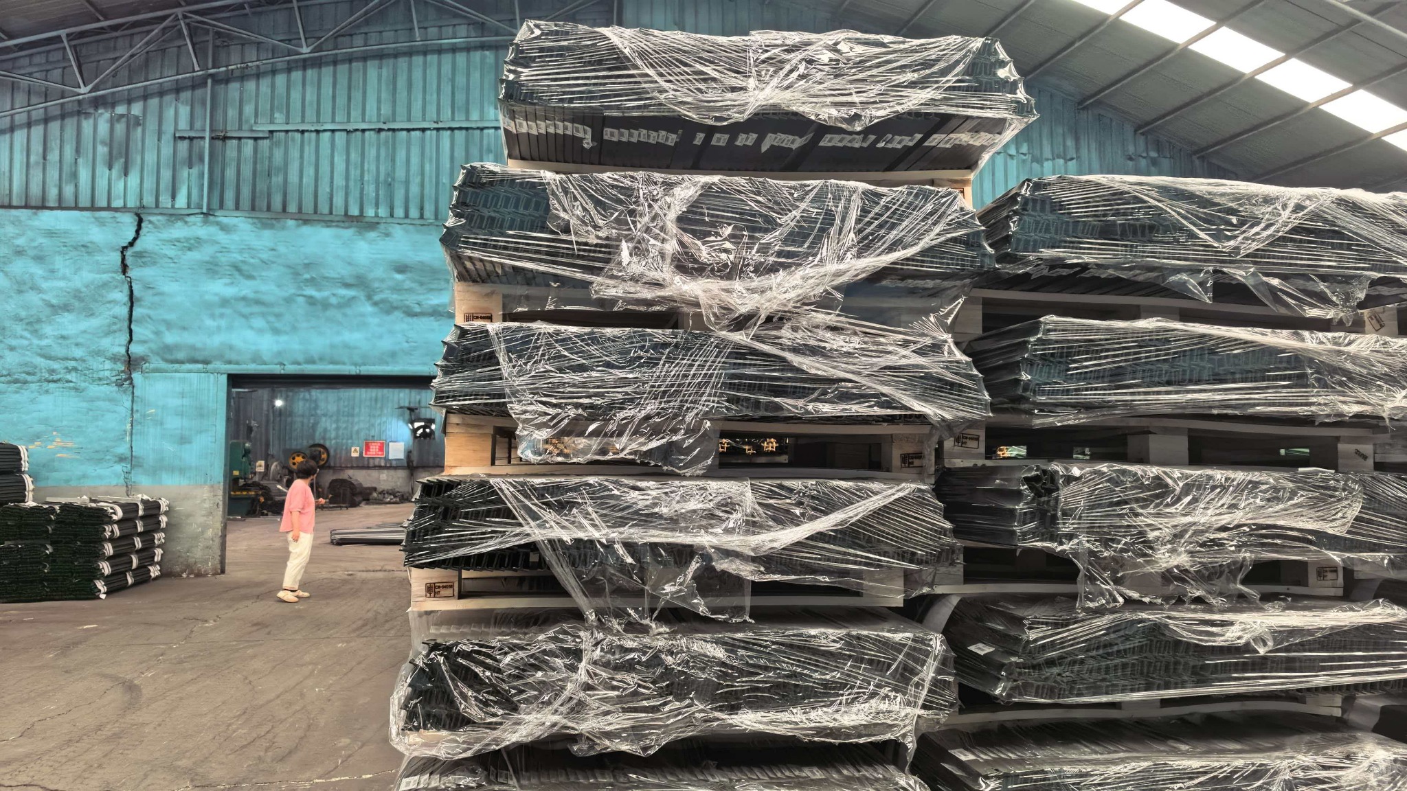 Steel T posts stacked on wooden pallets with protective wrapping inside the KUNYU workshop